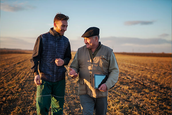 two men walking in a ploughed field one is holding a tablet device