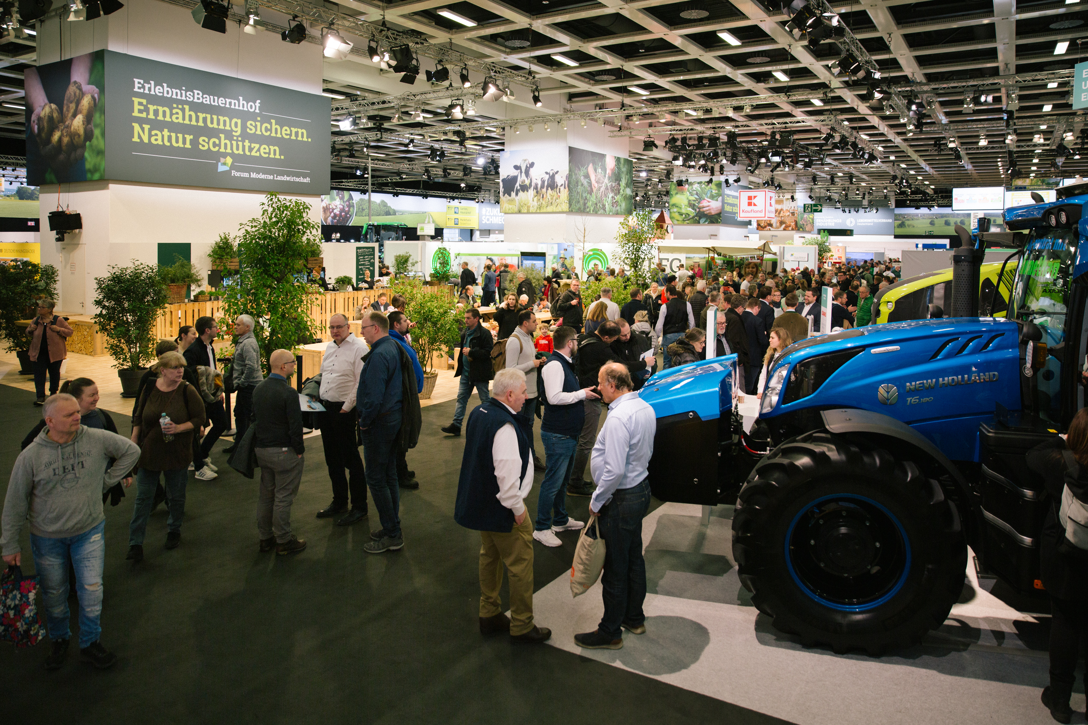 People gathered around a tractor at an agricultural show, observing the machinery and engaging in conversation.