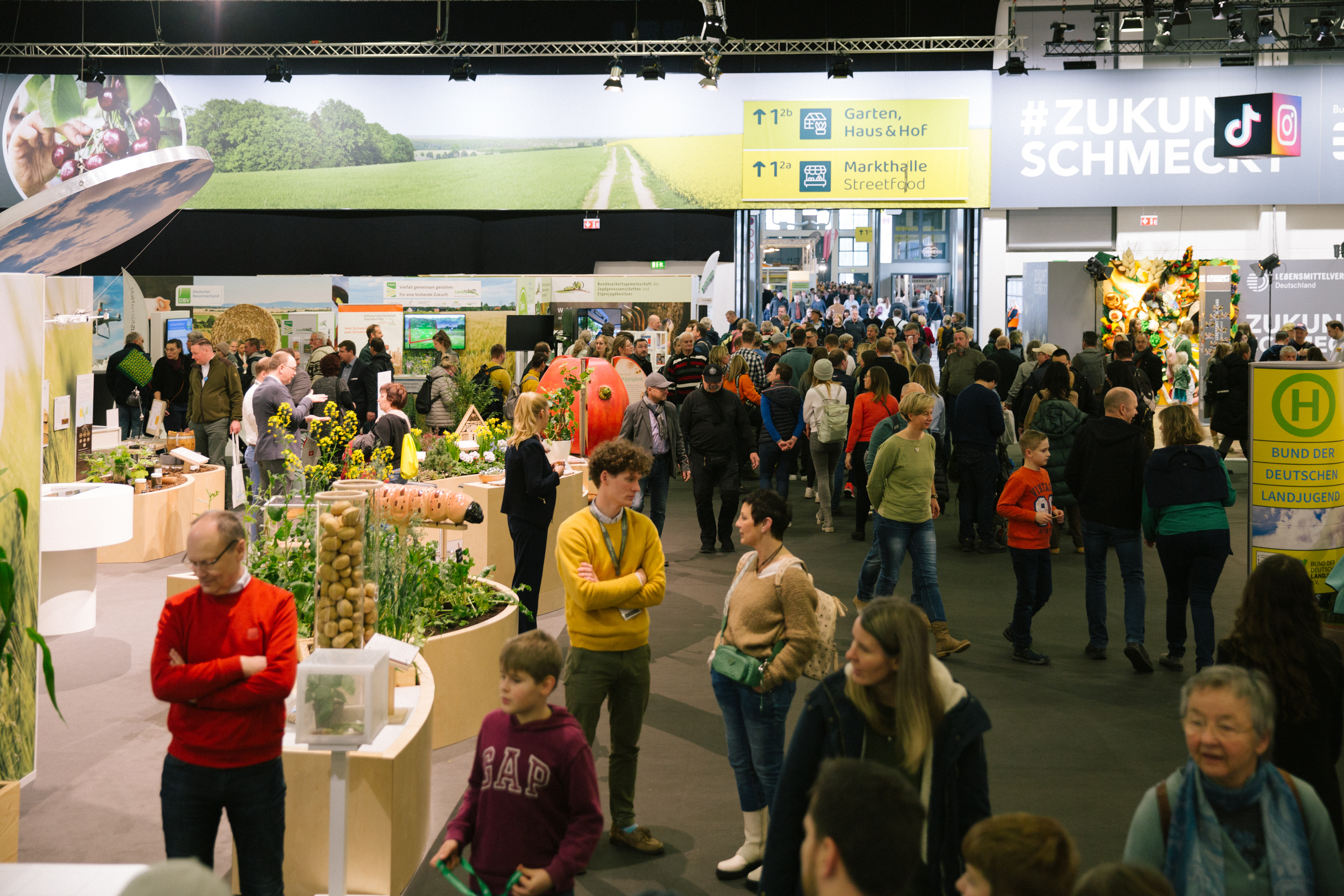 A diverse group of individuals gathered at an indoor exhibition, engaging in various activities and exploring the displays.