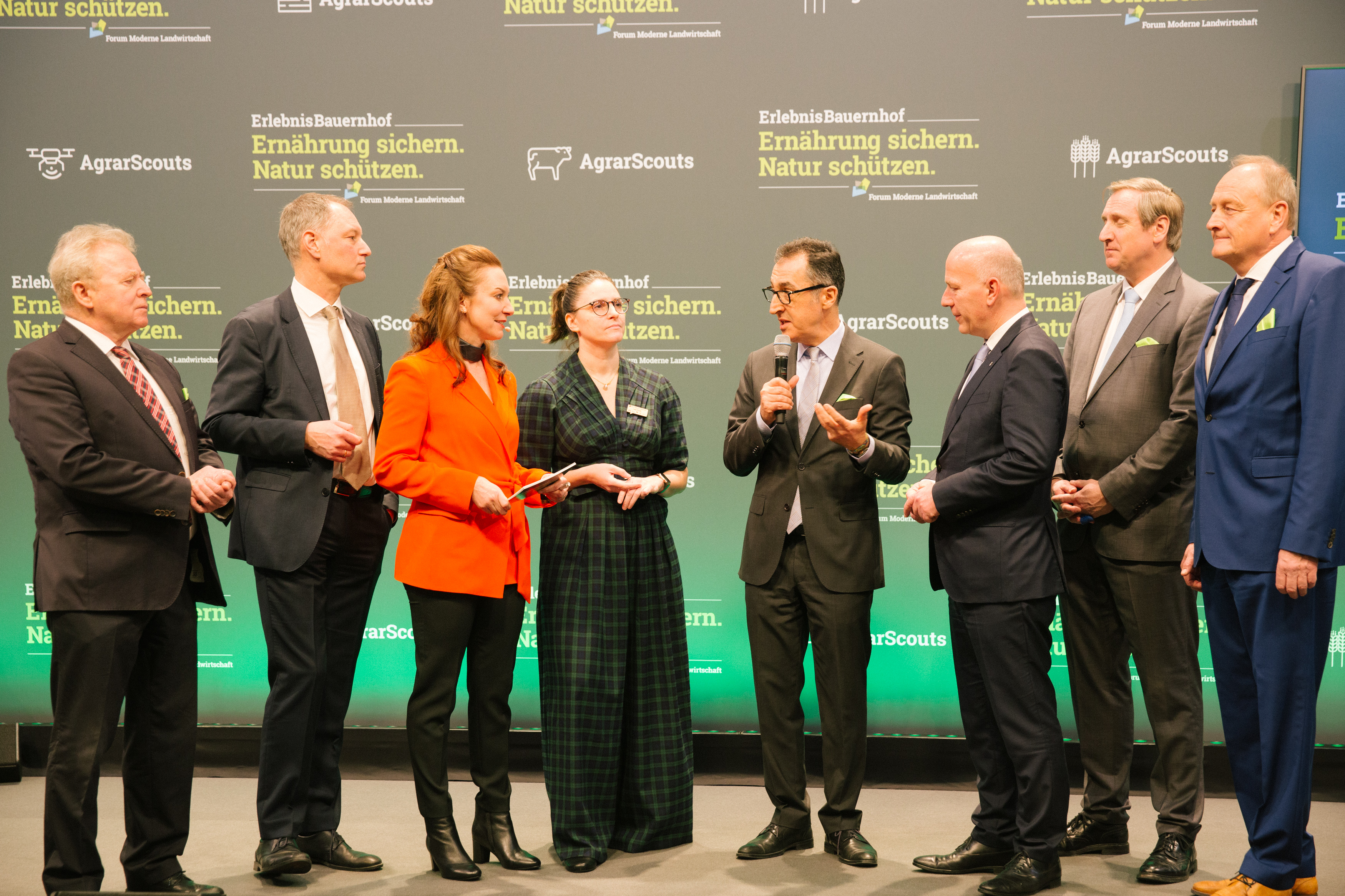 A diverse group of individuals standing together on a stage, showcasing unity and collaboration.