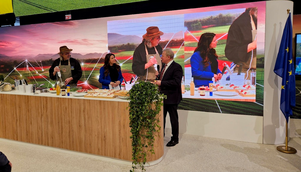 A man and woman standing in front of a large screen, possibly engaged in a presentation or event.