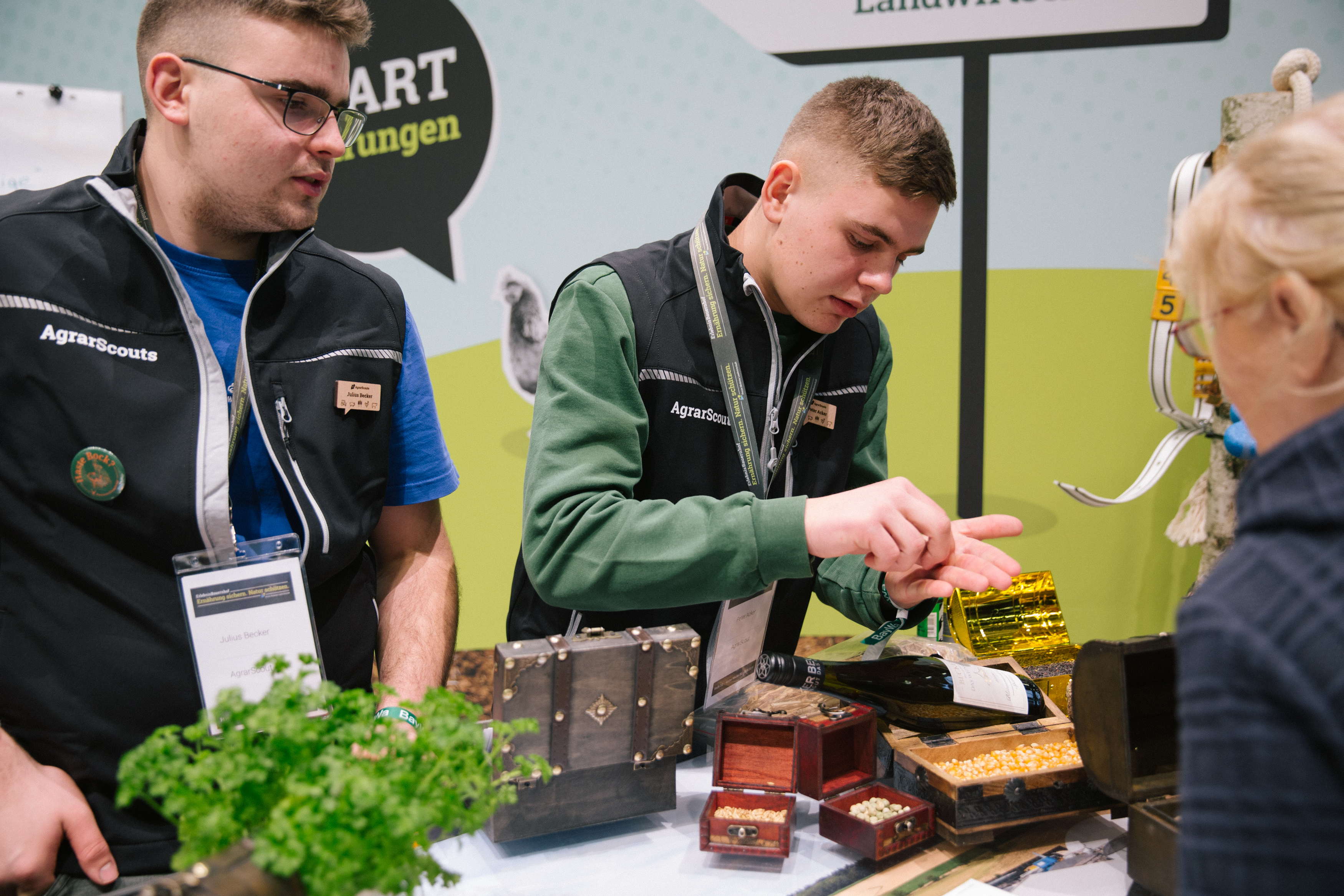 Two men examining a table with various plants, possibly discussing their features and arrangement.