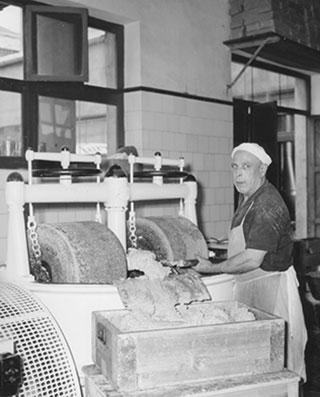 a man standing beside a machine in a factory, circa 1800s
