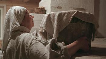 Naine hoidmas riidega kaetud tammeastjat, mida kasutatakse leivateol.