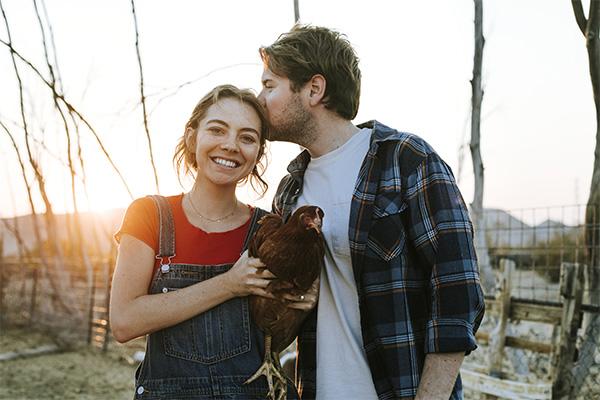 a young farming couple holding a chicken