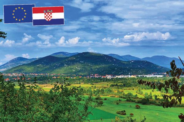 Croatian landscape of fields and mountains with the flags of Croatia and the EU